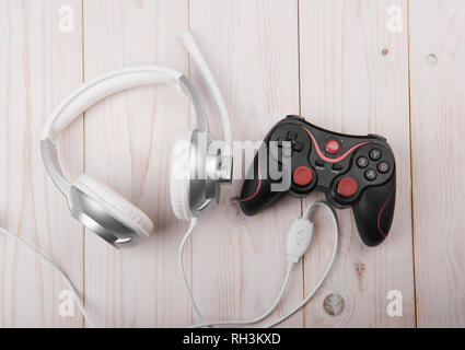remote and headphones for video games on a light wooden background Stock Photo