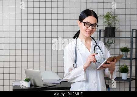 young female medical nurse using tablet computer in hospital office. Stock Photo