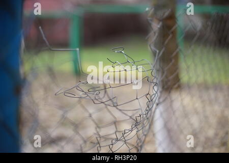 Closeup of a torn or broken steel mesh with a blurry colorful background. Selective focus. Perspective. Stock Photo