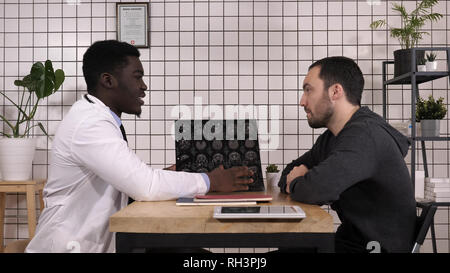 Intellectual healthcare professional with white labcoat showing mri to patient. Stock Photo