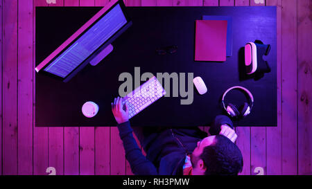 Tired hacker sleeping near computer while computer processing. Stock Photo