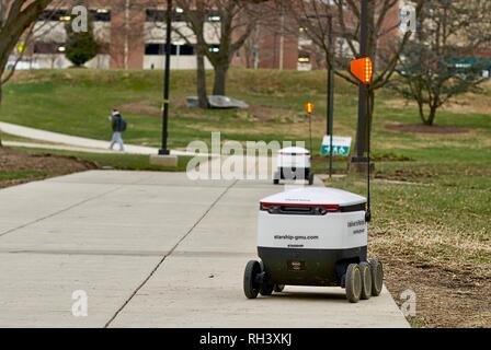 Fairfax, Virginia, USA - January 29, 2019: Two autonomous food delivery robots travel enroute to customers on George Mason University's main campus. Stock Photo