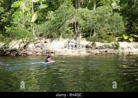 Young girl paddles on a boogie board down a river alone, Finch Hatton, Queensland 4756, Australia