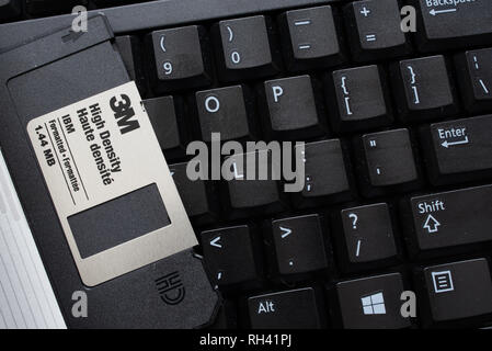 A black computer keyboard with a black 3M 3.5 inch floppy disk for data storage. Stock Photo