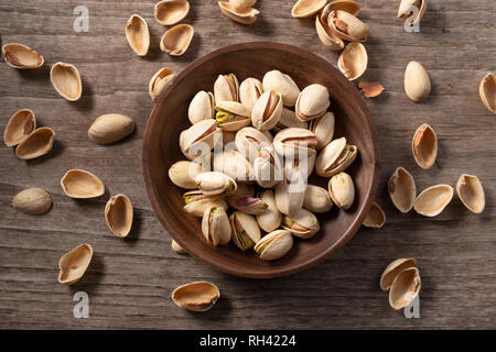 Pistachio nuts whole with husks cracked open on wooden table. Pistacia vera