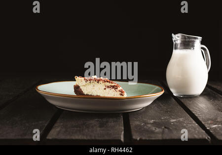 Photo of chocolate bio cheesecake in a retro plate with milk on wooden background. Dark food Photography of sweet and illuminated dessert. Stock Photo