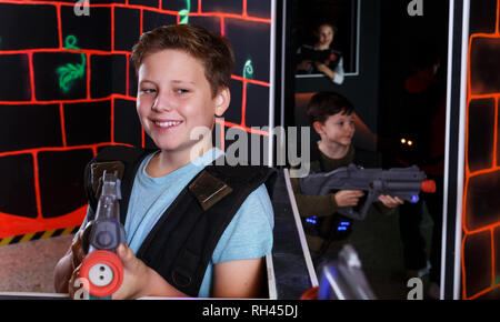 Foto Stock Excited boy aiming laser gun at other players during