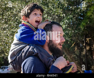 A boy sits on his father’s shoulders as they watch Dauphin Island’s first People’s Mardi Gras Parade, Feb. 4, 2017, in Dauphin Island, Alabam. Stock Photo