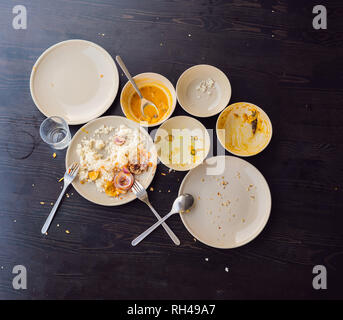 The remains of food in plates, crumbs on the table after lunch or dinner Stock Photo