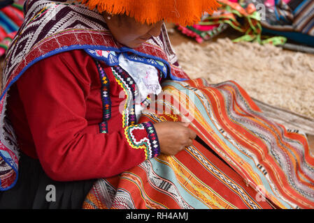 Pisac, Cusco, Peru - Oct 20, 2018: Quechua woman demonstrating traditional weaving techniques at a market in the Sacred Valley. Stock Photo