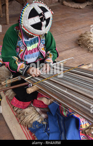 Pisac, Cusco, Peru - Oct 20, 2018: Quechua woman demonstrating traditional weaving techniques at a market in the Sacred Valley. Stock Photo