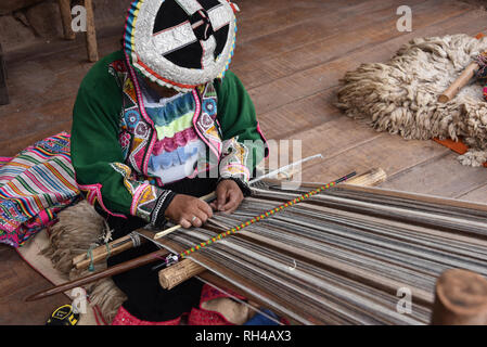 Pisac, Cusco, Peru - Oct 20, 2018: Quechua woman demonstrating traditional weaving techniques at a market in the Sacred Valley. Stock Photo