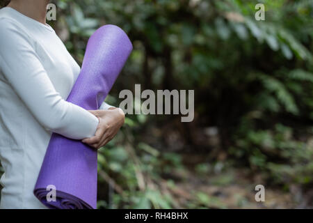 Women wearing a white yoga dress are rolling yoga at the waterfall. Stock Photo