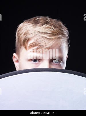 Young boy with light brown hair looking over the top of a circular cloth Stock Photo