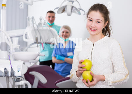 Portrait of happy teen girl in modern dental clinic with fresh apples in hands Stock Photo