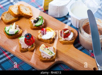 Assorted homemade crostini appetizers with different filling served on wooden cutting board Stock Photo