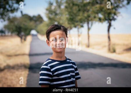 Portrait confident boy on sunny rural road Stock Photo