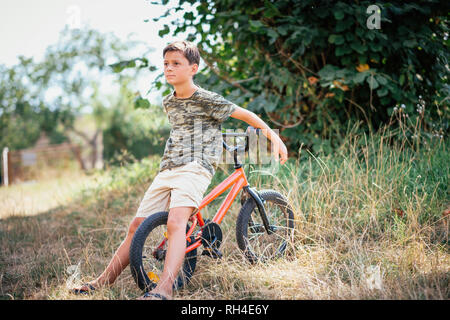 Boy with bicycle in grass Stock Photo