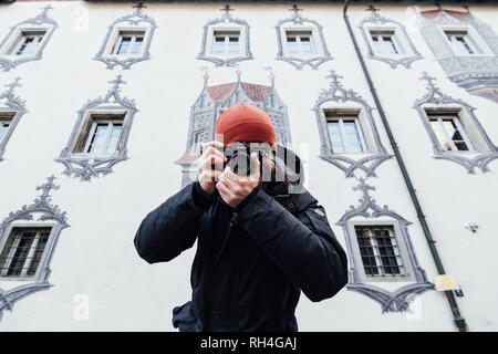 FUSSEN, GERMANY - DECEMBER 2018: man in orange hat taking pictures at the backyard of Hohes castle. Stock Photo