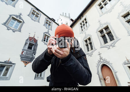 FUSSEN, GERMANY - DECEMBER 2018: man in orange hat taking pictures at the backyard of Hohes castle. Stock Photo