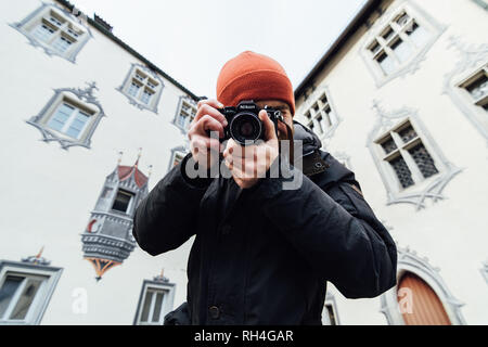 FUSSEN, GERMANY - DECEMBER 2018: man in orange hat taking pictures at the backyard of Hohes castle. Stock Photo