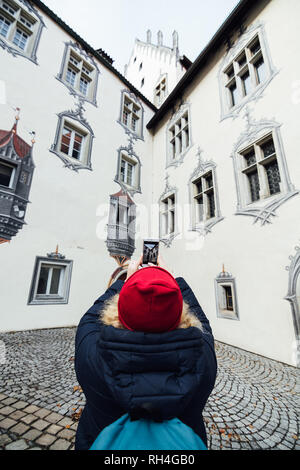 FUSSEN, GERMANY - DECEMBER 2018: woman in red hat taking pictures at the backyard of Hohes castle. Stock Photo