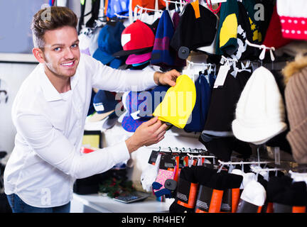 Young man choosing new knit cap in sports store Stock Photo