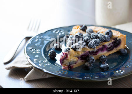 slice of blueberry lemon tart on blue antique plate with fork, napkin, and glass of milk. Stock Photo