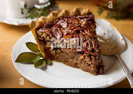 slice of pecan pie on white antique plate with silver serving spatula Stock Photo