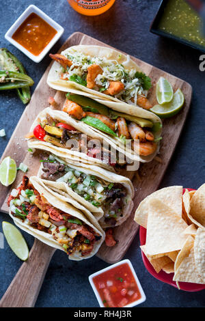 taco sampler on wooden board with tortilla chips and salsa Stock Photo