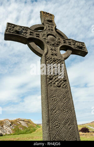 The intricately carved St Johns cross (replica) reaching to the heavens with blue sky and fluffy clouds. Iona Abbey, Scotland UK. Stock Photo