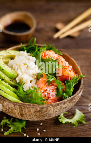 Hawaiian poke coconut bowl with grilled salmon fish, rice and avocado. Healthy food Stock Photo