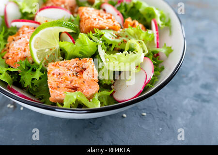 Healthy lunch salad with baked salmon fish, fresh radish, lettuce and lime Stock Photo