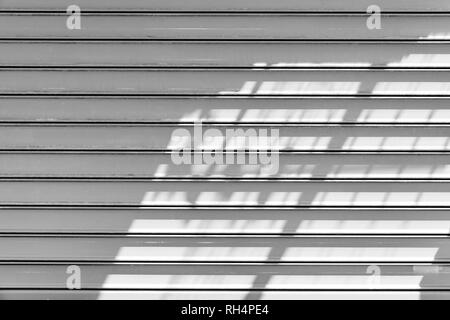 White metal roller shutter door with shadows pattern. Background photo texture, front view Stock Photo