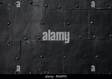Old black submarine hull fragment, grungy metal sheets with rivets, background photo texture Stock Photo