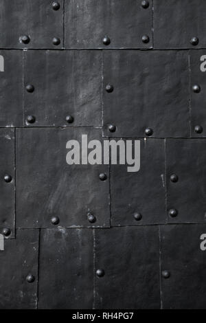 Black submarine hull fragment, grungy metal sheets with rivets, vertical background photo texture Stock Photo