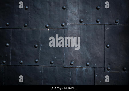 Old black ship hull fragment, grungy metal sheets with rivets, background photo texture Stock Photo