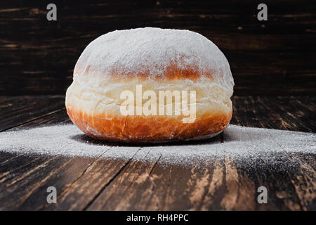 Freshly made doughnut, heavily covered in powdered sugar on a an old wooden Stock Photo