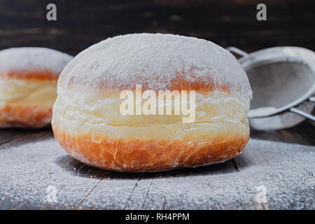 Freshly made doughnuts, heavily covered in powdered sugar on a an old wooden table Stock Photo