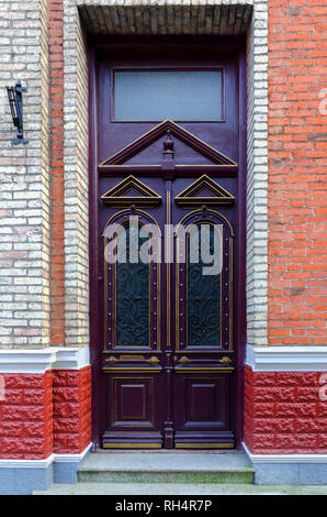 Front door, double purple front doors with geometric elements, and glass. Brick wall. Stock Photo