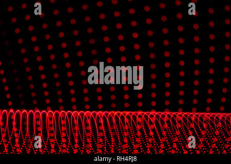 Several red dotted lines with abstract shapes. Light painting photography. Red spots on black background. Stock Photo