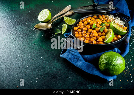 Vegan indian food, Sweet Potato and Chickpea curry, Chana Masala, with lime slices and spices on dark green stone table top ciew copy space Stock Photo