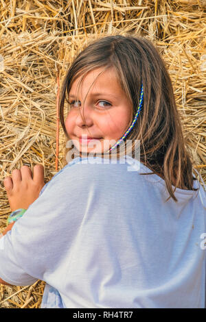 little girl playing alone in the field with straw bales Stock Photo