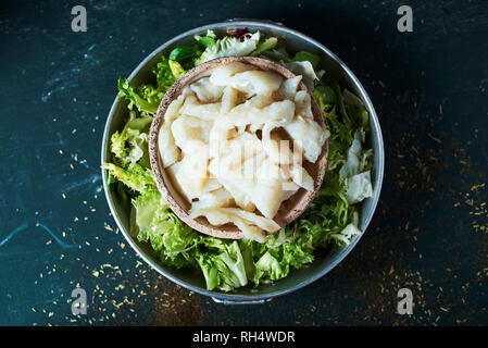 high angle view of some bowls with the ingredients to prepare xato, a catalan salad with desalinated salt cod and escarole endive, on a rustic dark gr Stock Photo