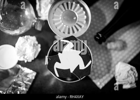 trash can with recycle symbol surrounded by reusable waste materials like plastic paper and glass, concept of reducing damage to the environment Stock Photo