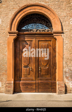 Old wooden red house door in the historical centre in Ferrara, Italy Stock Photo