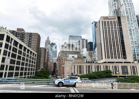 New York City, USA - July 26, 2018: Police car controlling the traffic on the Brooklyn Bridge with skyscrapers of Manhattan in the background in New Y Stock Photo