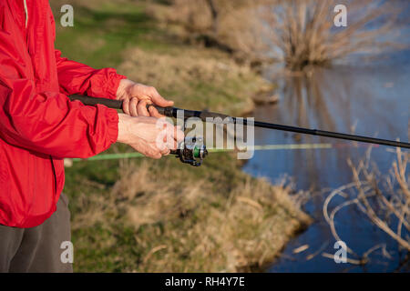 Fishing rod fly fishing in fisherman's hand. Evening fishing. Closeup hands. Stock Photo