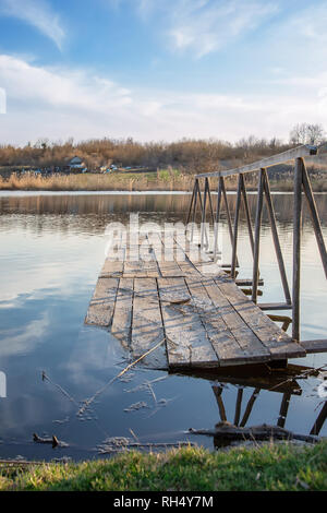 Wooden bridge on the lake. Dawn over the water. Peaceful atmosphere in nature. Empty place for text, quote or saying. Stock Photo