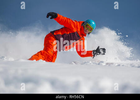 A man on a snowboard make s turn in deep powder snow in the ski resort of Courchevel in the France Alps. Stock Photo